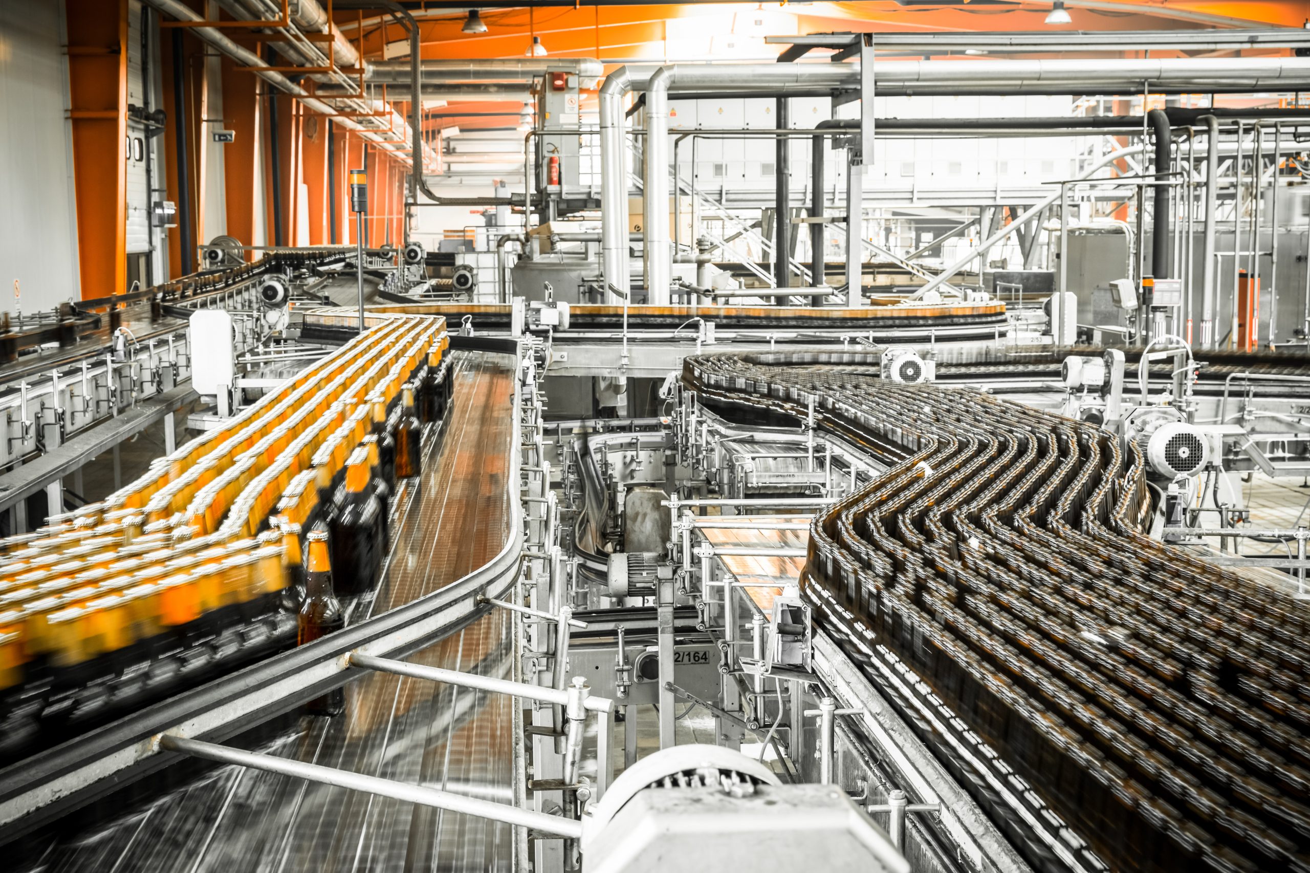 Conveyor belts move rows of bottled drinks through an automated factory